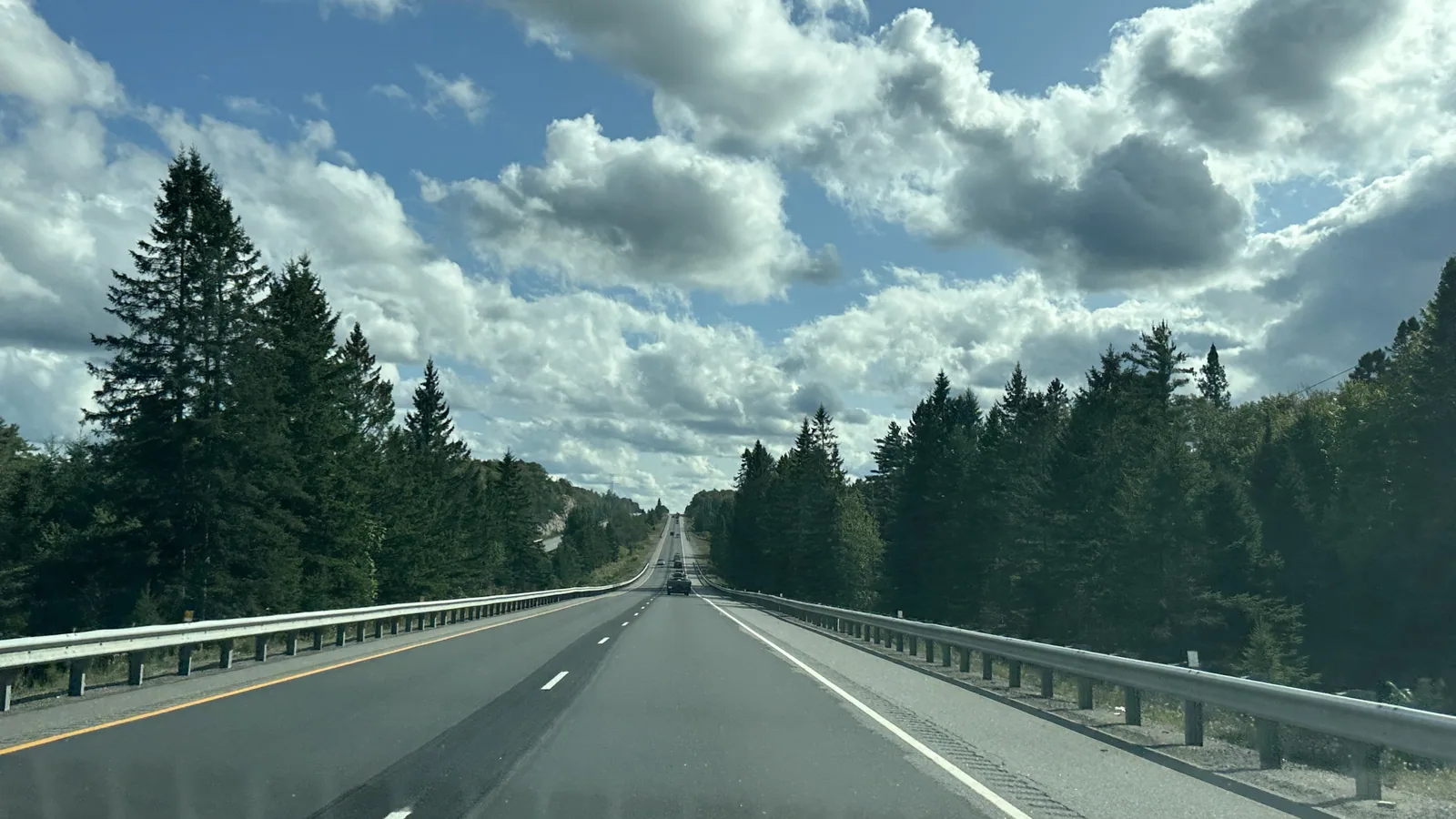 Highway 60 stretching through forest under big clouds